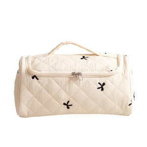 Quilted cream vanity case with black bow embroidery and large U-shaped zip opening