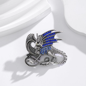 Silver dragon brooch with blue rhinestones on a white minimalist studio background