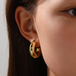 Close-up of elegant gold hollow C-shaped hoop earrings with a high-polished mirror finish