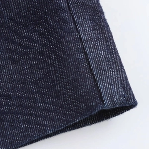 Vue macro montrant la texture du denim bleu foncé et les coutures détaillées de la robe