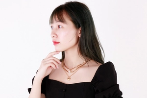Détail d'un collier doré multicouche avec perle baroque et pendentif en cœur
