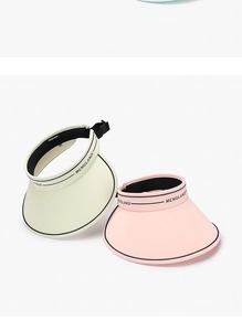 Detail view of adjustable sun visors in cream and pink with black brim piping and sweatband