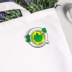Creative Green Tea Club enamel pin on a white canvas bag with lavender and watch scenery