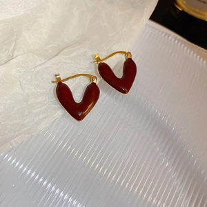 Macro shot of V-shaped heart earrings featuring deep red enamel and gold-plated metal