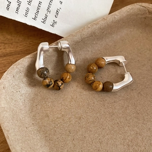 Gros plan de boucles d'oreilles en argent en U avec perles de pierre marbrée marron