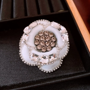 Macro shot of camellia fabric brooch with crystal petals and pavé diamond edges