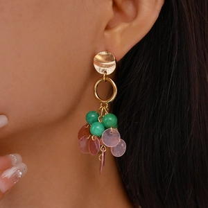 Detail of vintage gold earrings with green spherical beads and pink circular dangles