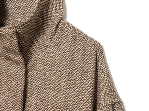 Dettaglio della spalla di una giacca in tweed marrone a spina di pesce con fibre
