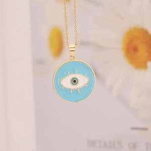 Detail of 18K gold-plated necklace featuring a blue enamel evil eye pendant with lashes