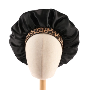 Detailed view of the leopard print elastic band and glossy black satin fabric on the sleep bonnet