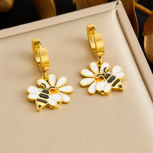 Detail of bee and daisy charm earrings in gold finish with enamel oil dripping work