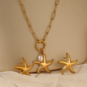 Golden starfish jewelry set with pearl necklace and stud earrings on beige display