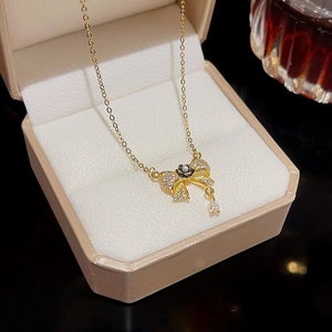Detail of bow pendant on gold chain with pavé zircon, black flower, and drop stone