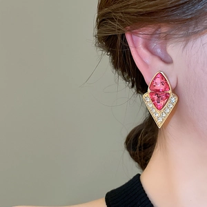 Close-up of luxury geometric pink stone stud earrings with diamonds on model