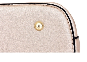 Detailed close-up of champagne leather handbag base with protective gold metal studs