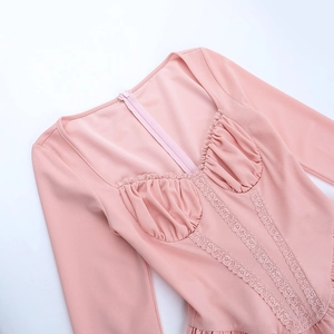 Detailed close-up of pink long-sleeved dress with heart-shaped lace collar and fine stitching