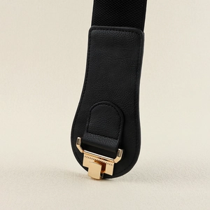 Detail of black leather and gold geometric metal buckle on an elastic wide waist belt