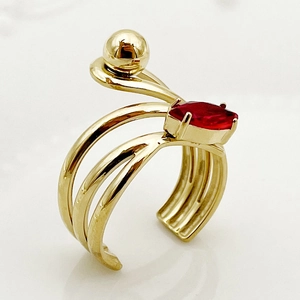 Detail of gold multi-layered open ring featuring a red marquise gemstone and gold bead accent