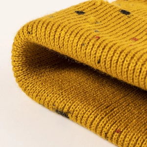 Primo piano di berretto lavorato a maglia giallo zenzero con macchie colorate e coste