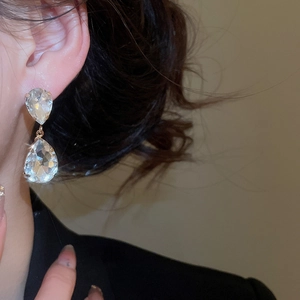 Close-up of model wearing luxury crystal water drop earrings with tassel design