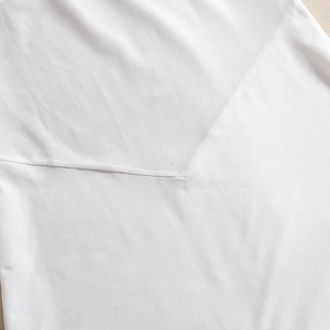 Detail of V-neck mesh splicing on white dress showing fabric texture and stitching