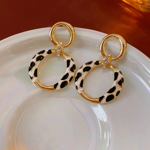 Close-up of gold leopard print hoop earrings with sparkling rhinestones on a white plate