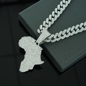 Close-up of a silver hip hop necklace with iced-out Africa map pendant on a black box