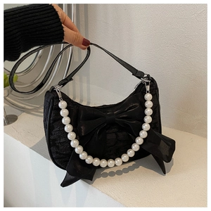 Close-up of black pleated fabric handbag featuring a large bow and white pearl handle