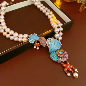 Macro detail of vintage double-layer pearl necklace with colorful enamel shell charms