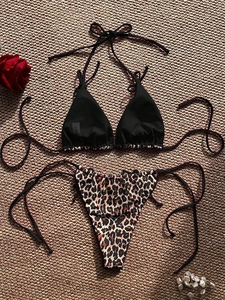 Detailed flat lay of black halter bikini top and leopard print tie-side bottoms with pearls