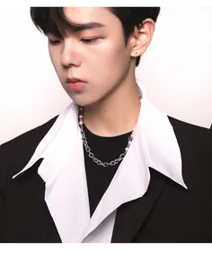 Close-up of asymmetric pearl and silver chain necklace on male model with black suit