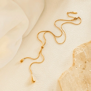 Detail of adjustable golden snake chain with teardrop tassel pendants on silk