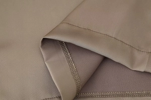 Detailed macro shot showing the fine stitching and satin texture of brown wide-leg pants