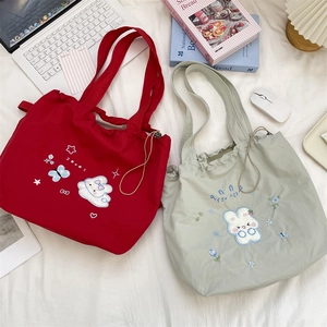 Close-up of floral embroidered canvas tote bags with drawstring closure and laptop accessories