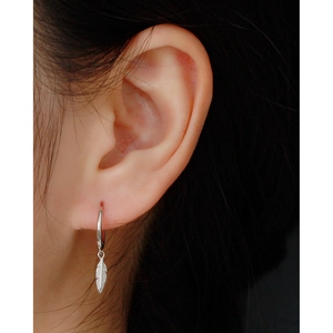 Close-up of S925 sterling silver hoop earring with detailed feather drop pendant on model