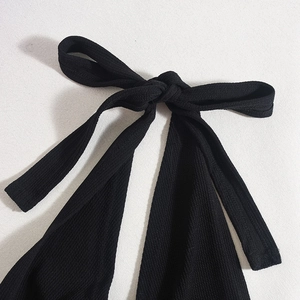 Detail eines schwarzen gerippten Stoffknotens an einem Neckholder-Kleid mit feiner Textur