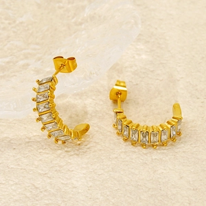 Detailed macro view of gold-plated U-shaped earrings with rectangular zircon inlay