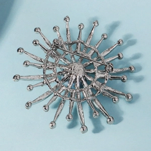 Macro detail of silver sunflower brooch with metallic spikes and pin closure on blue back