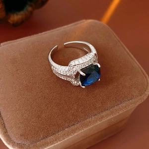 Gros plan d'une bague réglable argentée avec zircon bleu sur un écrin en velours brun