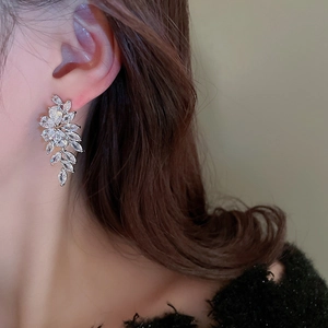 Close-up of elegant leaf-shaped silver earrings with sparkling cubic zirconia on a model