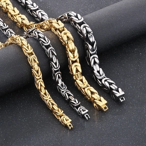 Detail of Byzantine weave chain necklaces in gold and silver finish on dark background