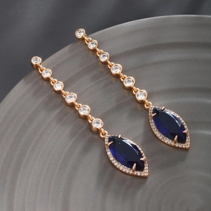 Macro shot of rose gold earrings with blue marquise cut stones and white zircon accents
