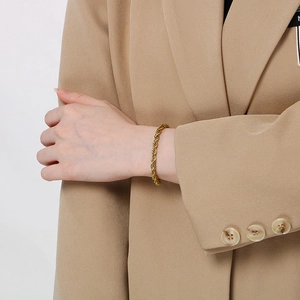 Detail shot of a golden twist rope bracelet showing the textured metal on a wrist