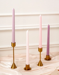 Primer plano de candelabros de metal dorado con velas cónicas moradas y blancas