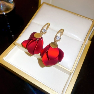 Close-up of red fabric flower earrings with gold hooks in a jewelry box display