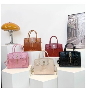 Macro detail of crocodile texture and smooth leather mix with chic tassel on top handle bag