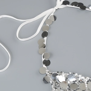 Detailed macro view of silver sequins and stitching on a white strap evening dress