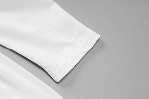 Dettaglio della cucitura fine e trama jersey sui polsini di un abito bianco a maniche