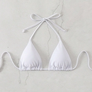 Detailed view of white halter bikini top with bow tie and ruched texture on marble