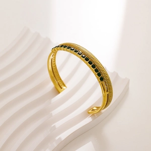 Detail of gold-plated stainless steel bracelet with wheat pattern and green zircon stone